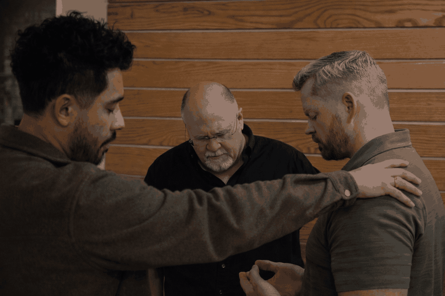 Three men praying together at a Faith & Business Roundtable