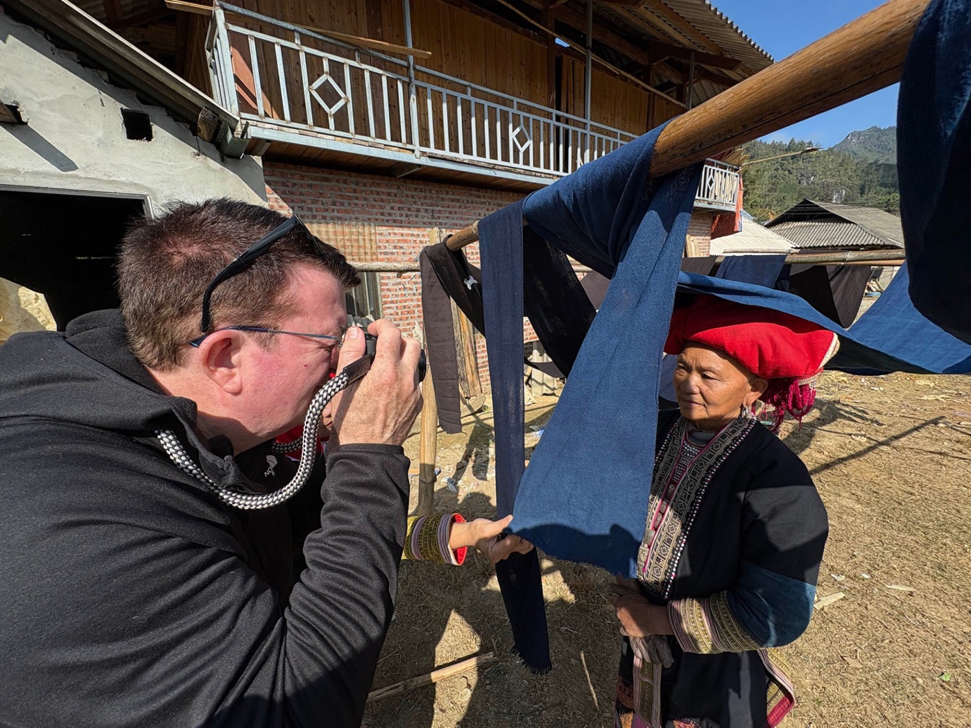 Workshop participant photographing a woman in a red headscarf in northern Vietnam