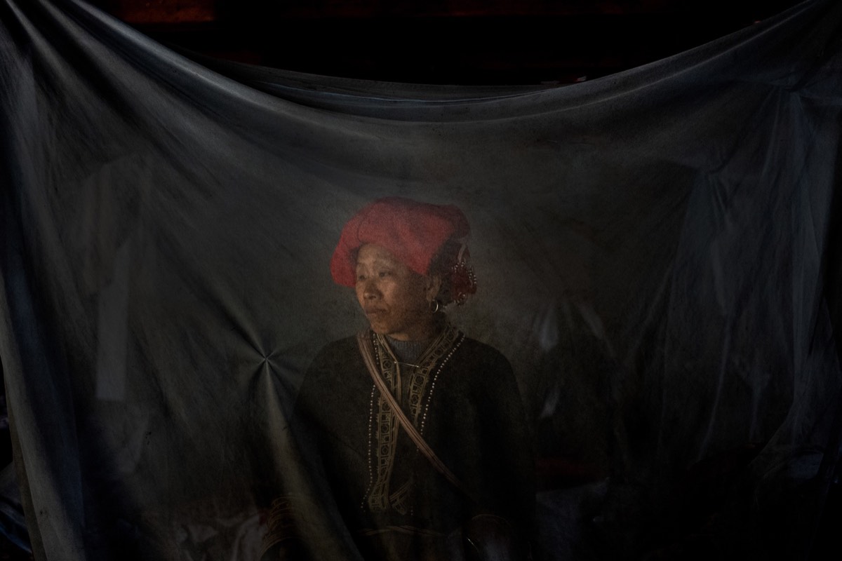 Woman in traditional clothing framed by dark fabric in northern Vietnam