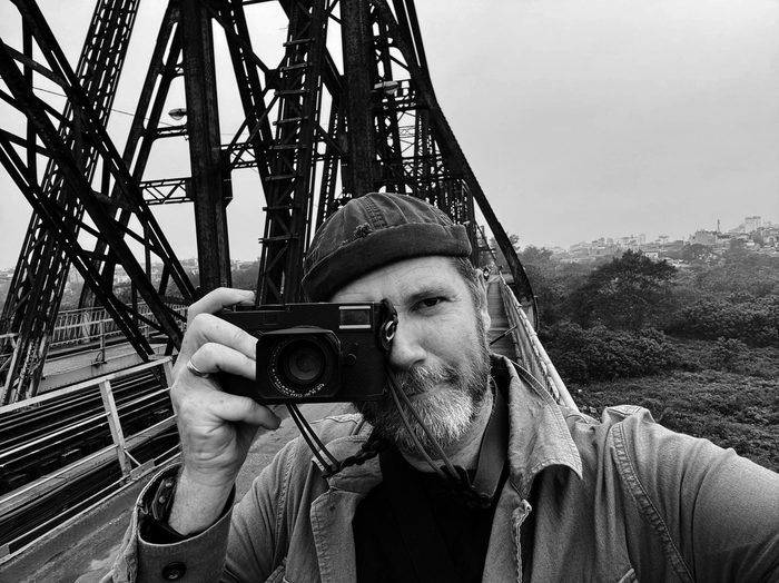 Justin Mott photographing on Long Bien Bridge in Hanoi, Vietnam