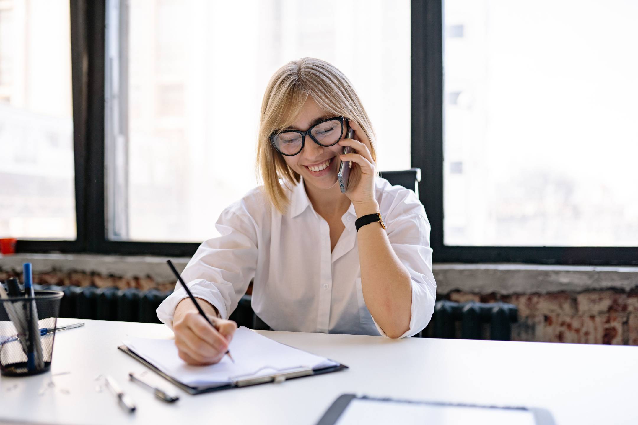 Legal assistant taking notes while on the phone