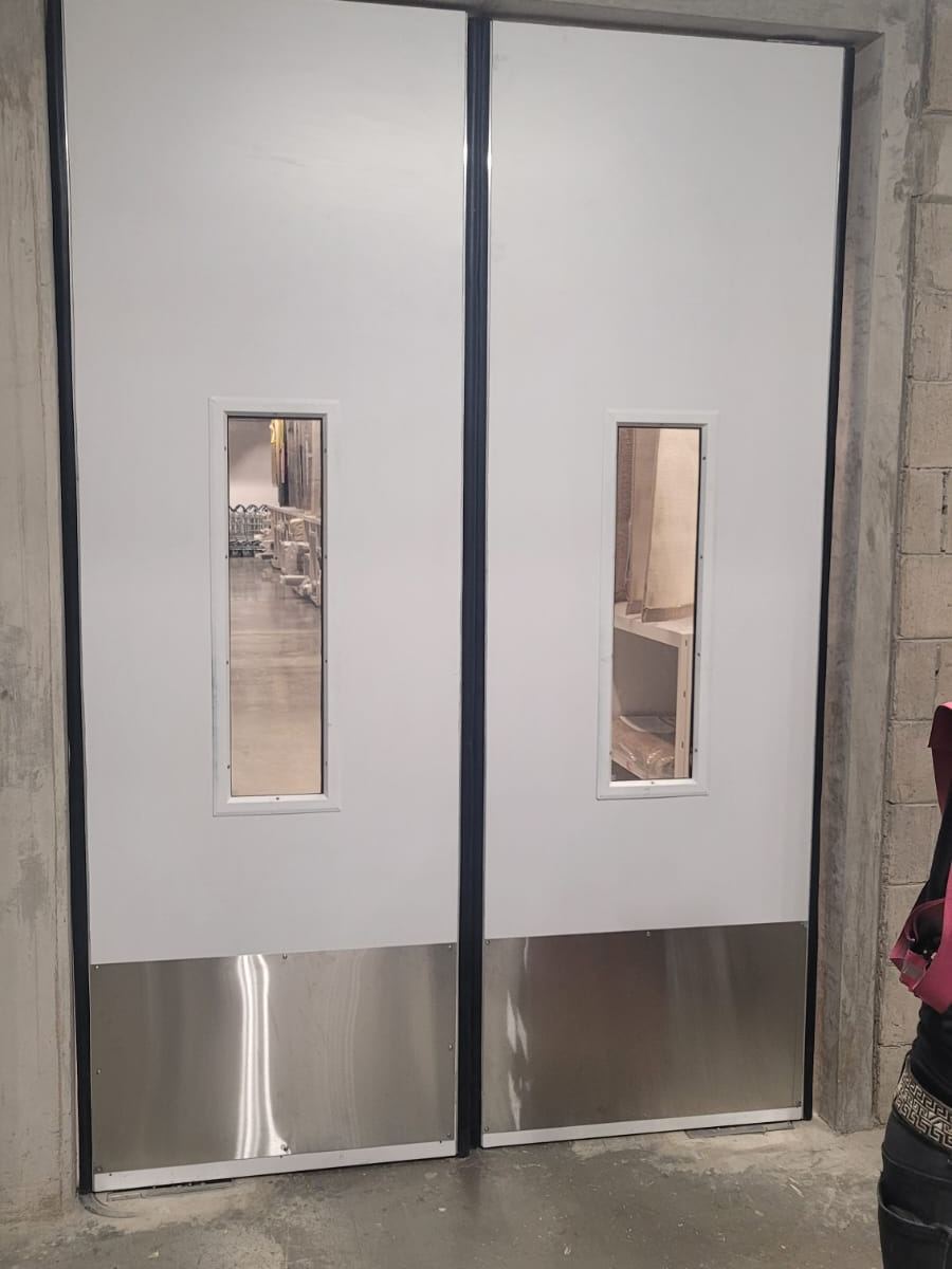 Puertas dobles de servicio con mirillas y protección inferior de acero inoxidable
