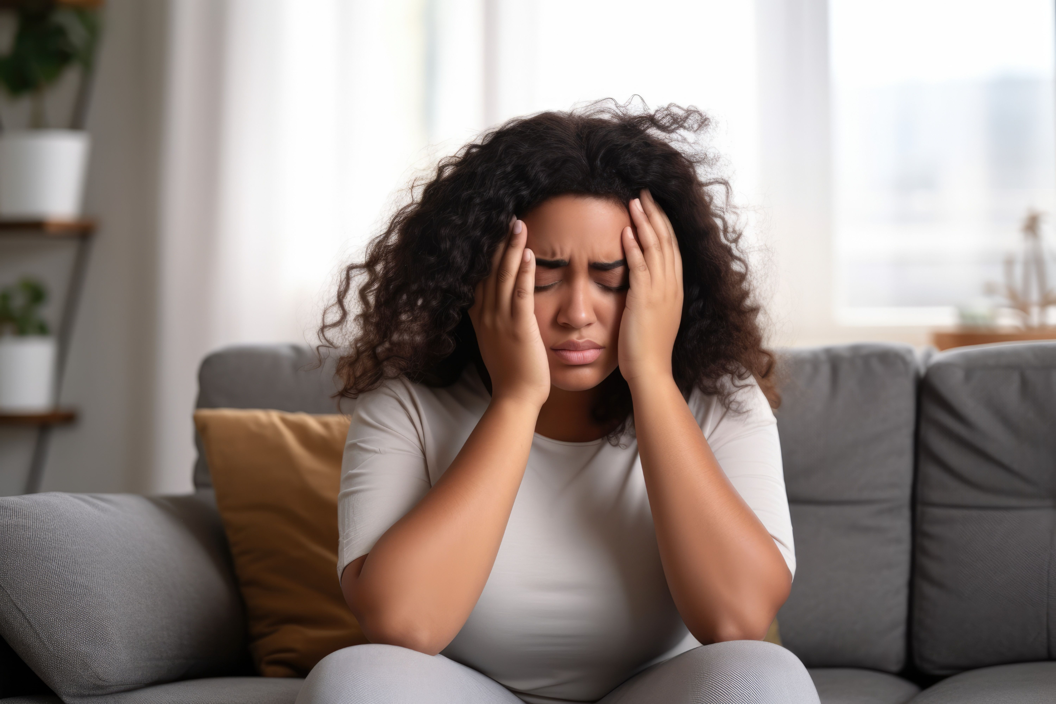 Frustrated woman holding her head while sitting on a couch