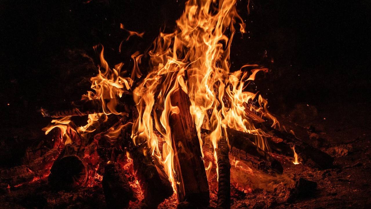 A bonfire burning brightly at night, flames rising freely from the wood — a symbol of permission to feel your anger instead of smothering it