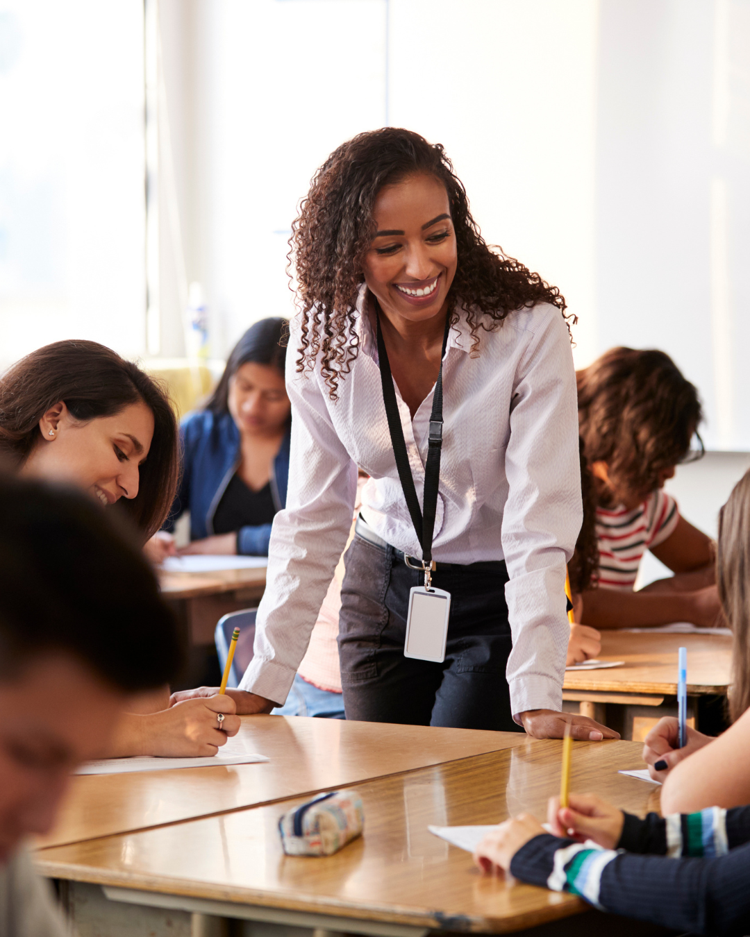 Teacher in a classroom working with students after passing the Educating All 