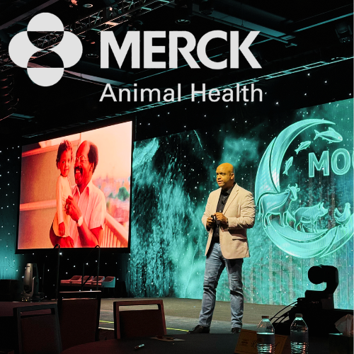 Healthcare keynote speaker Mike Veny presents onstage at a Merck Animal Health event with the company logo and conference screens behind him.