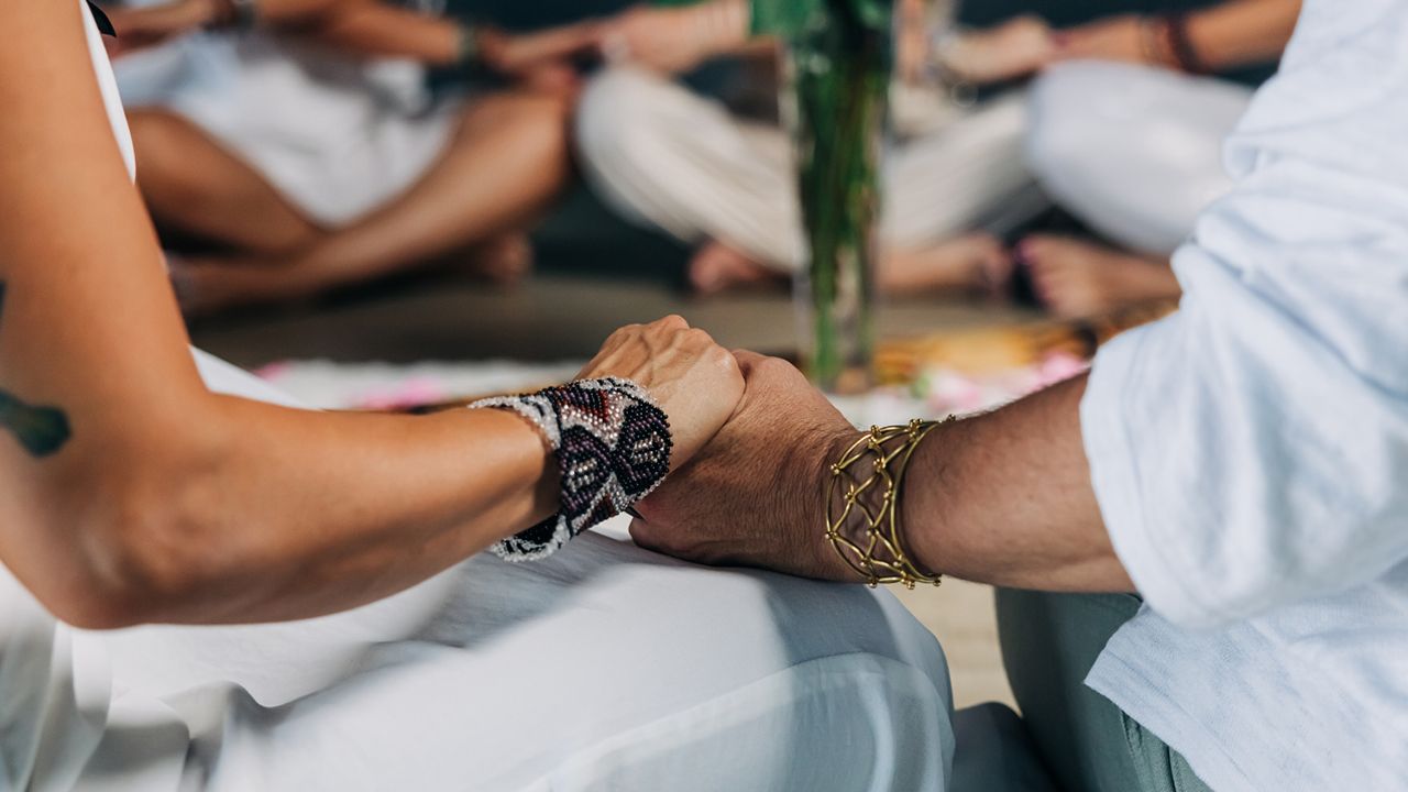 Close-up of two women holding hands during a women’s circle gathering focused on connection, reflection, healing, and community.