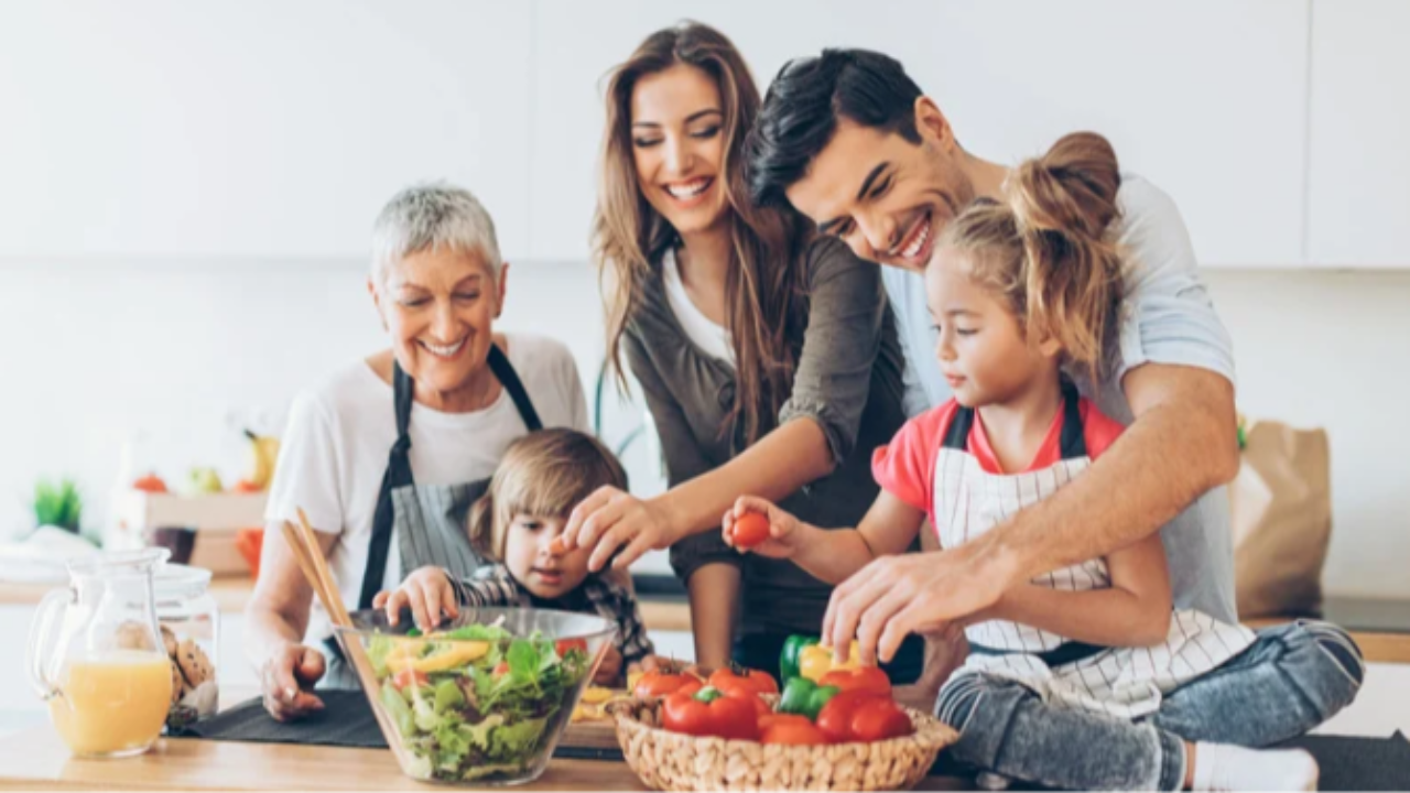 Adults and children preparing vegetables together in a kitchen