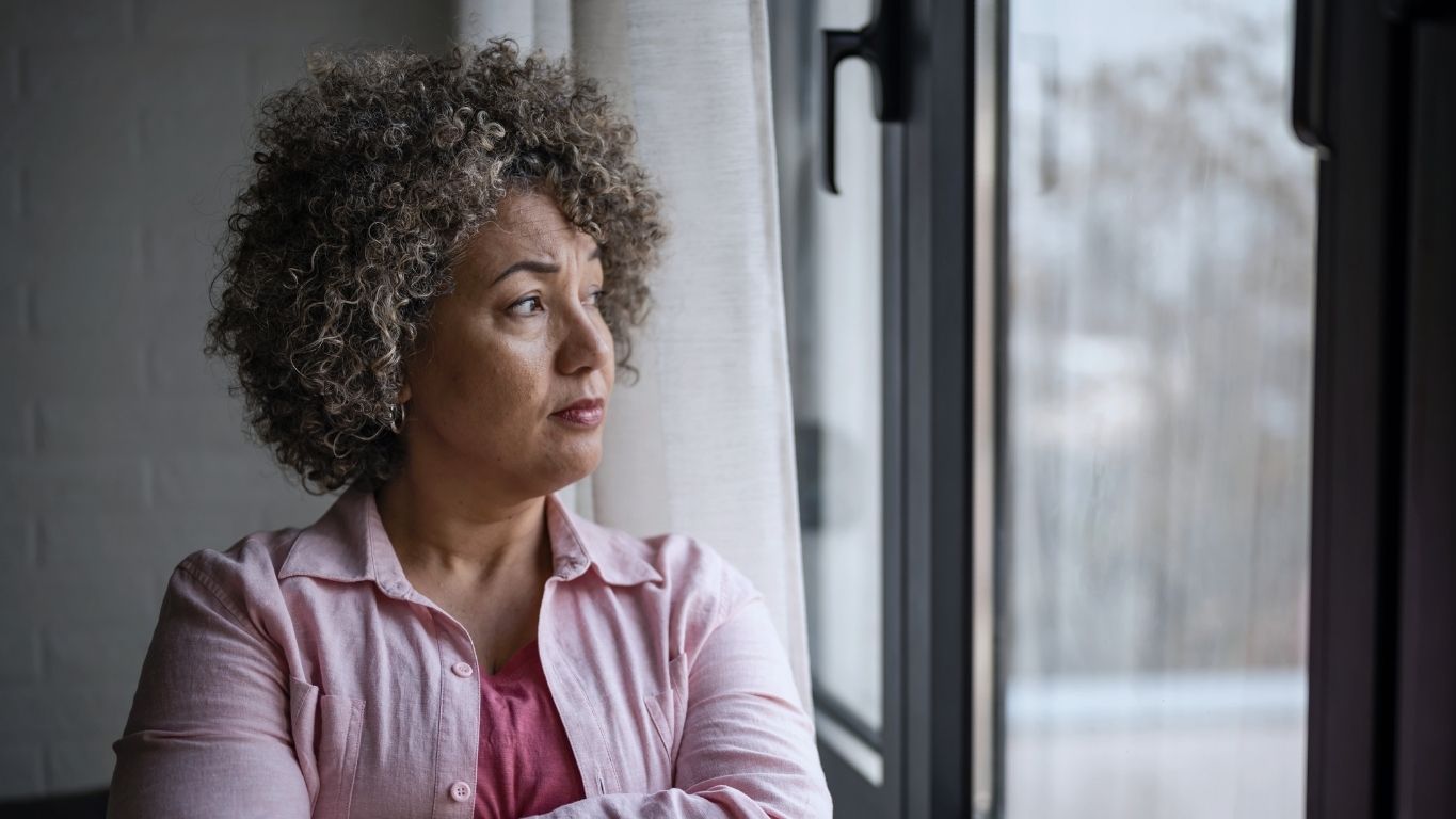 Thoughtful woman looking out a window at home