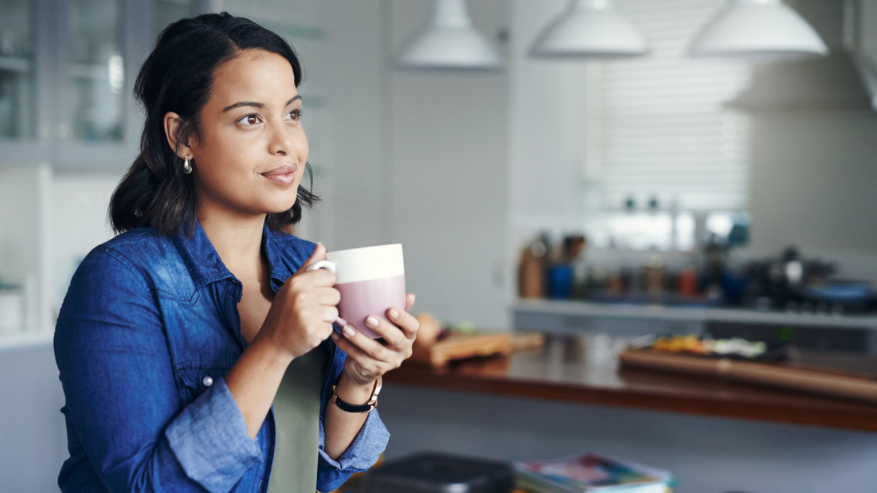 Person holding a mug and looking thoughtfully into the distance