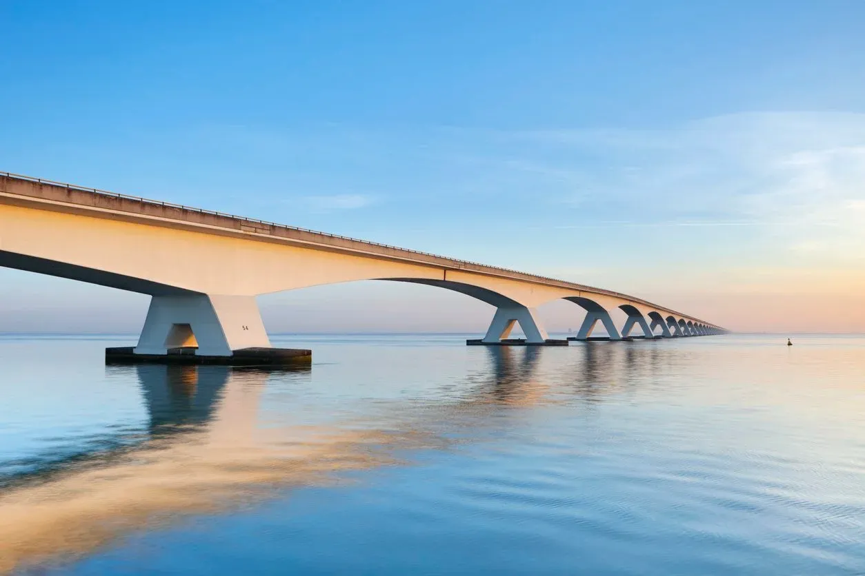 Long bridge stretching across calm water at sunset — building the bridge between today and tomorrow you