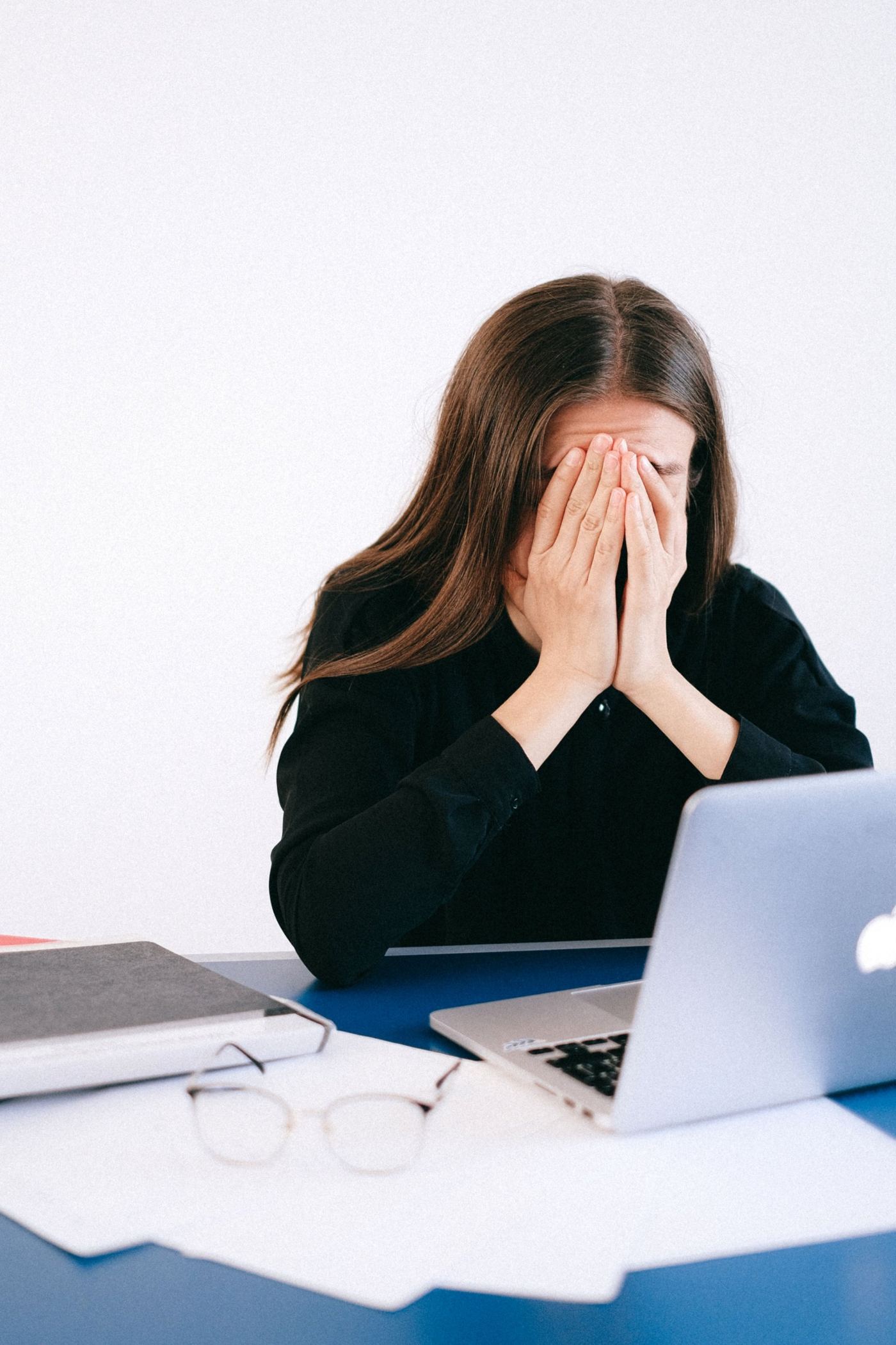 A woman at her desk with her hands over her face
