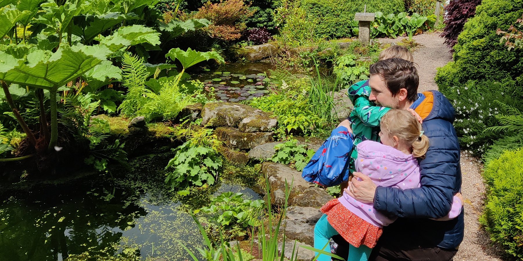 Dr. Danny O'Rourke in a garden with his two children beside a pond