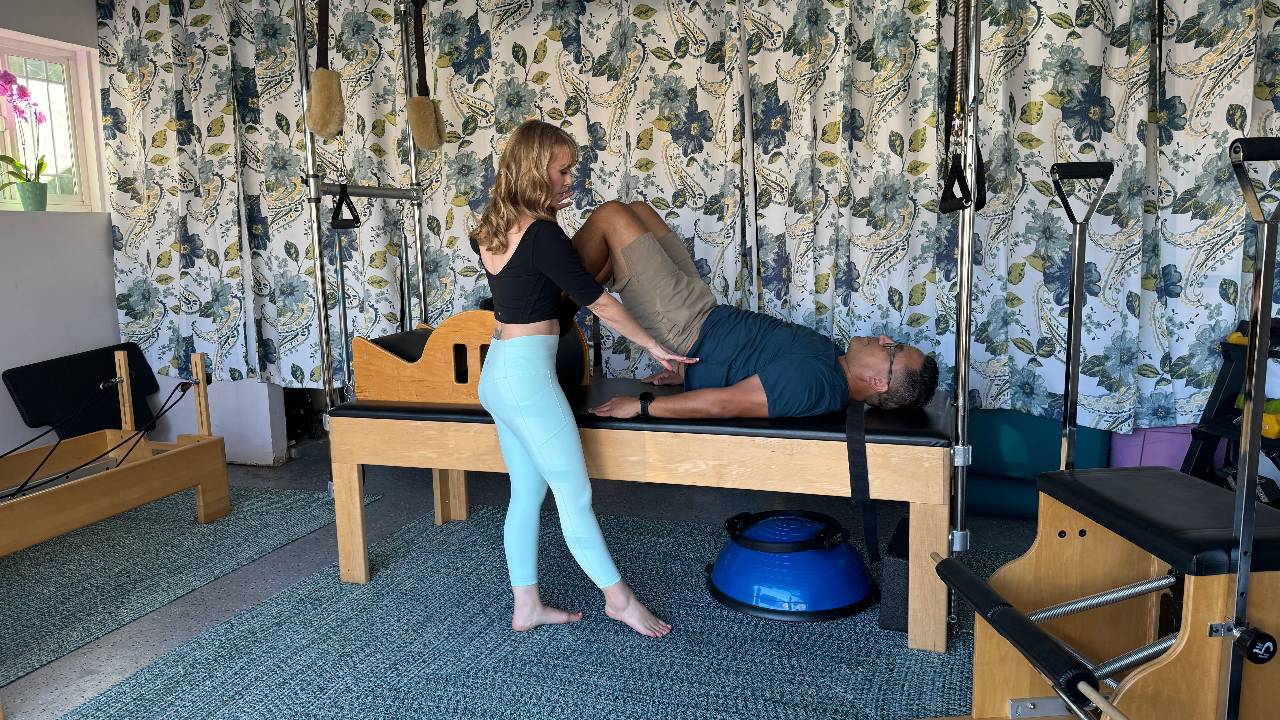 Man practicing Cadillac Pilates with an instructor for strength and mobility