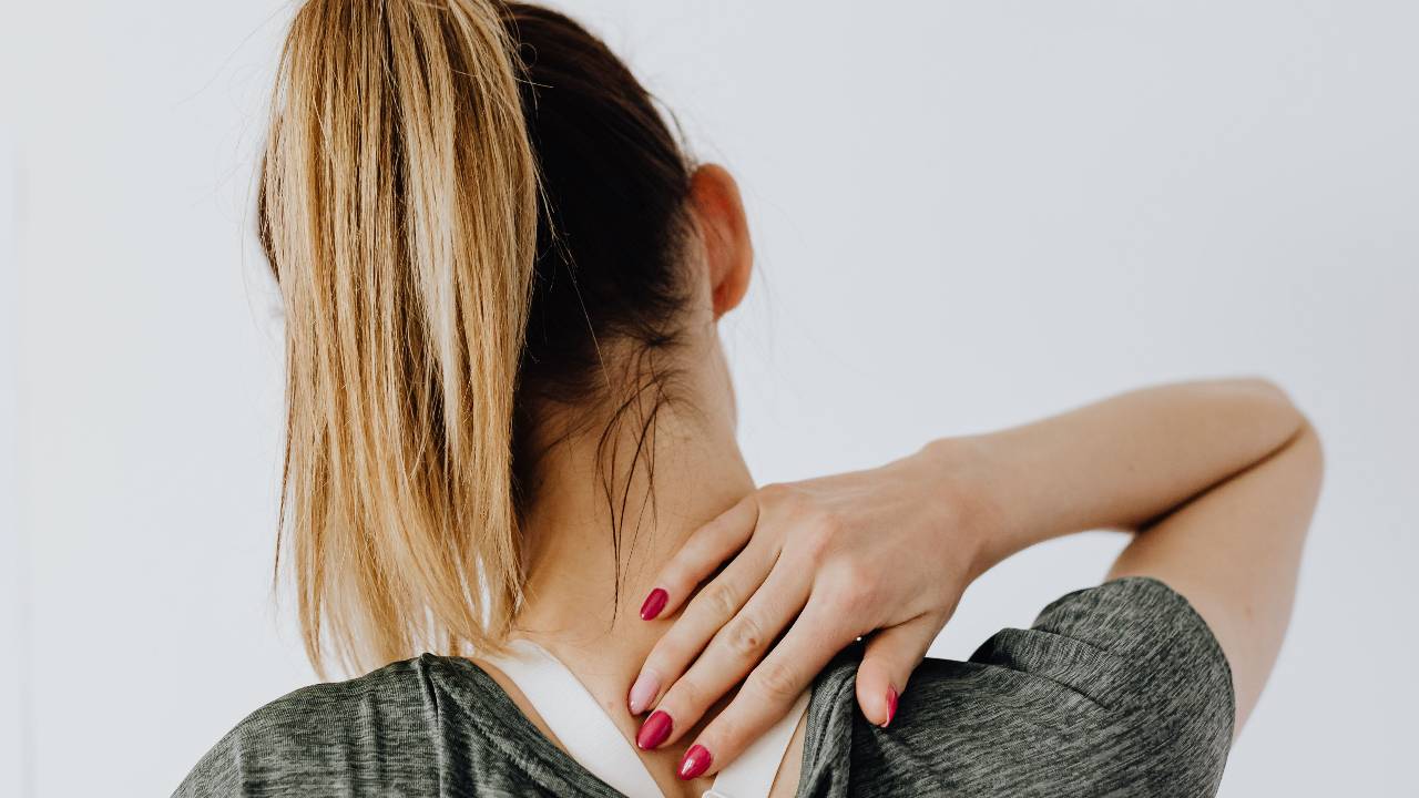 Woman stretching the base of her neck to relieve neck tension