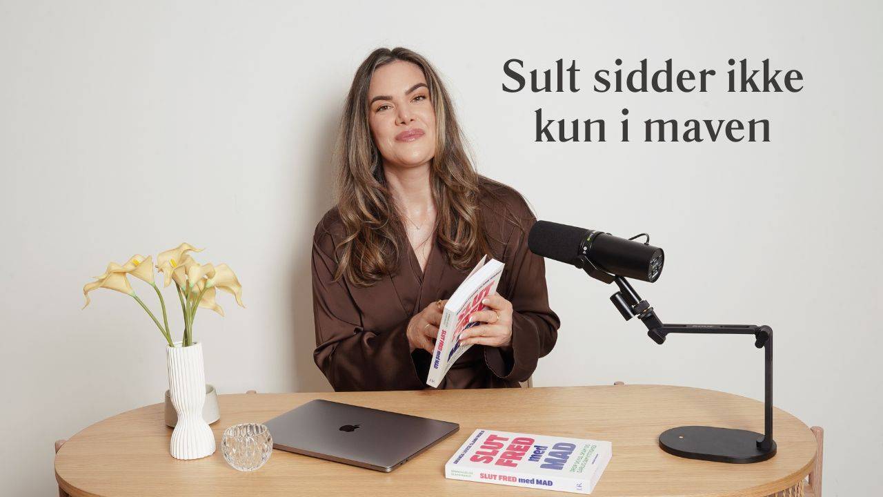 Amanda Louise ved sit skrivebord med bogen Slut Fred Med Mad. Titel: Sult sidder ikke kun i maven.