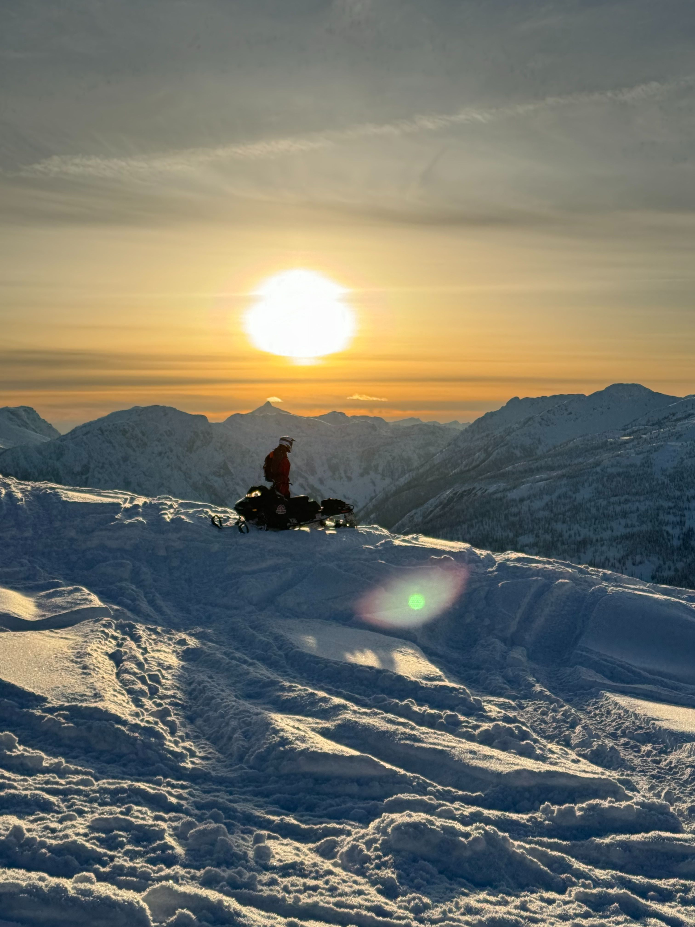 Octavio on a snowmobile in the mountains at sunset