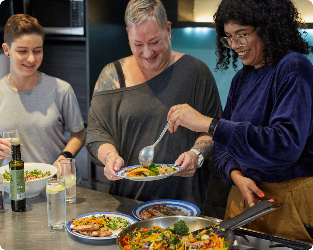 Three colleagues cooking and plating food together during a corporate team wellness session