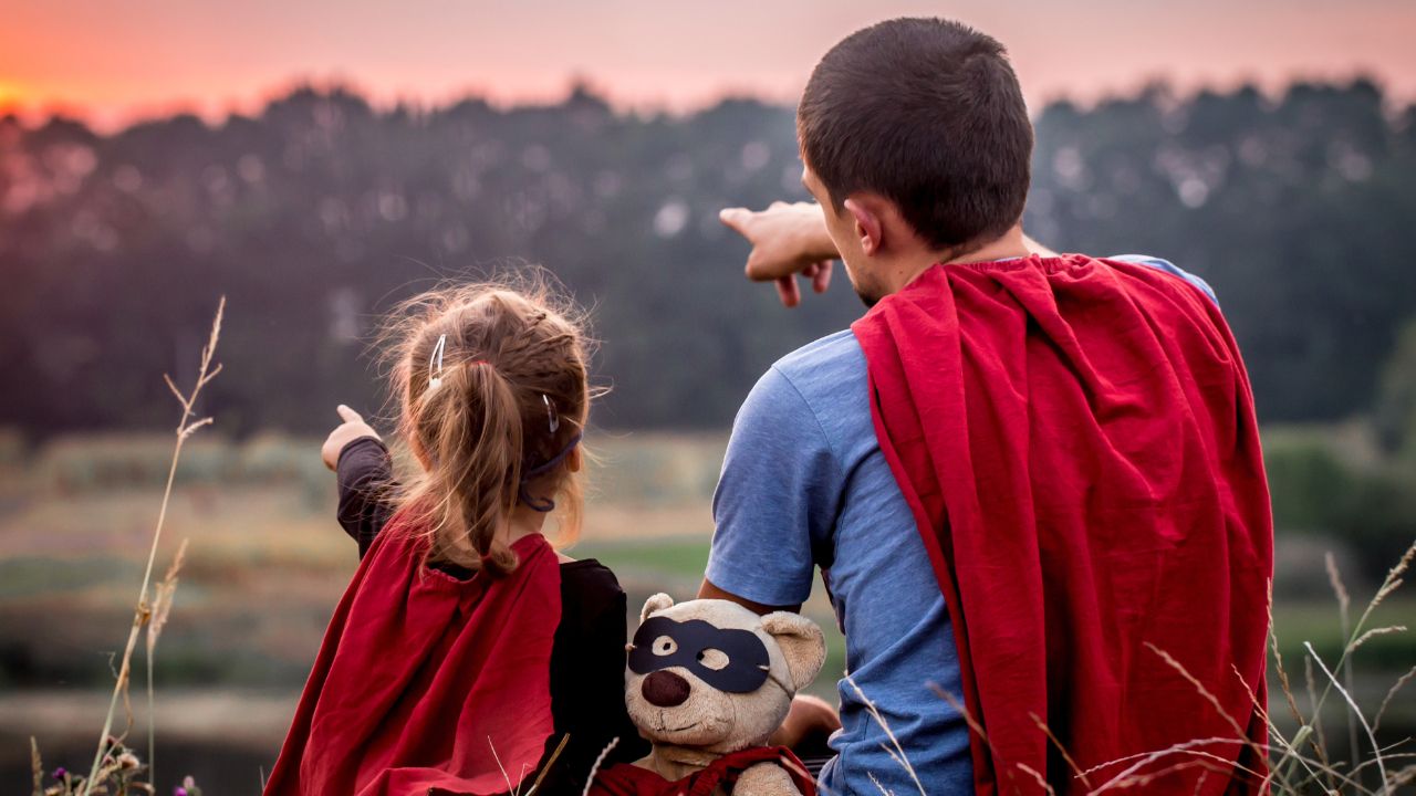 father and child wearing capes