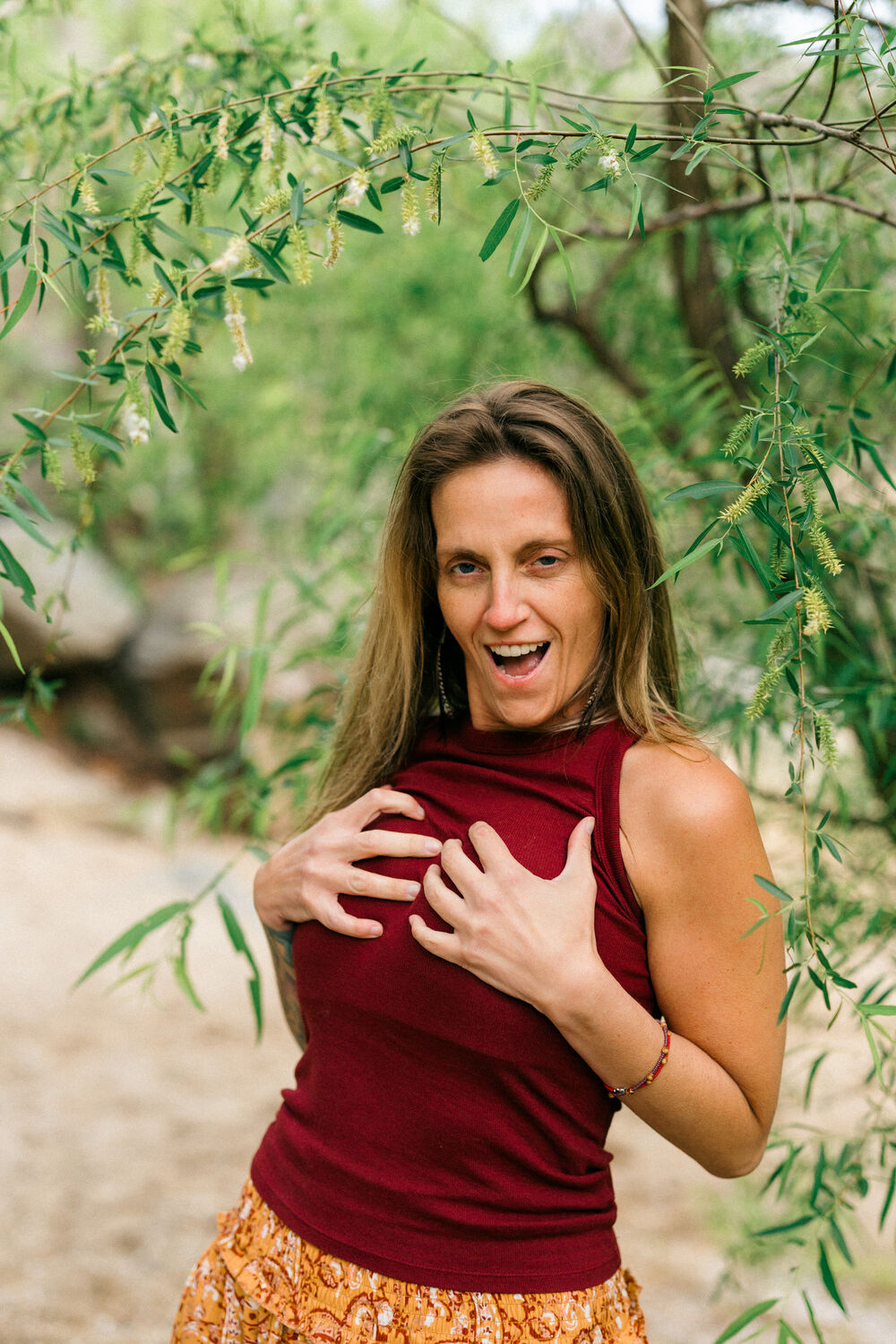 Jean-Marie laughing, hands at her chest, under the willow