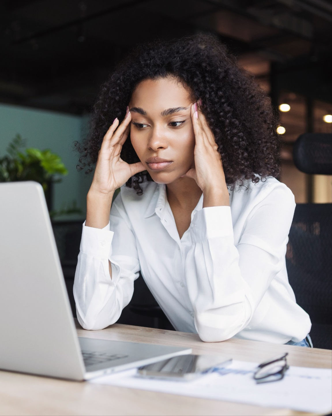 A woman frustrated at a computer rubbing her temples. 