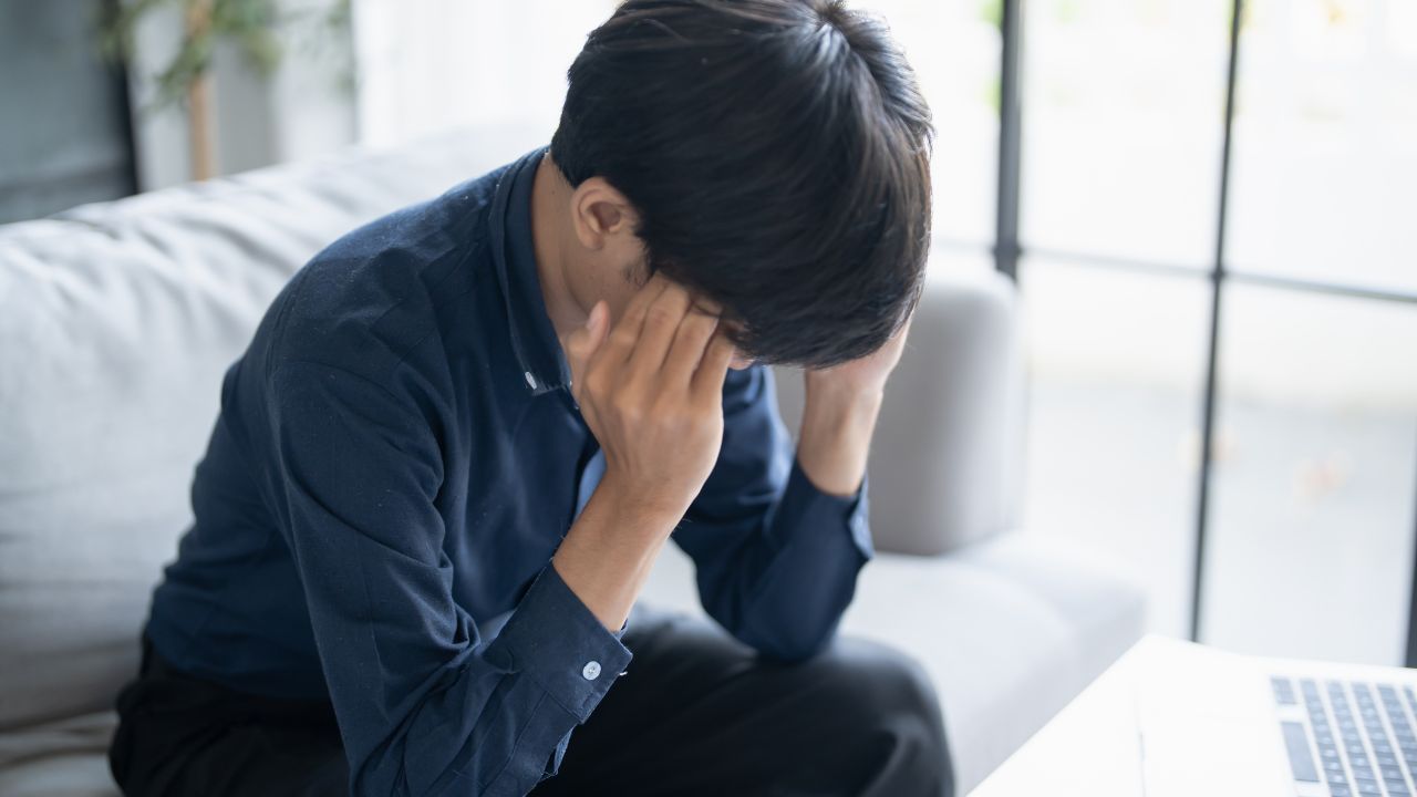 Person sitting on a couch with head in hands, illustrating emotional pain, overwhelm, anxiety, and the journey toward emotional healing through self-compassion.