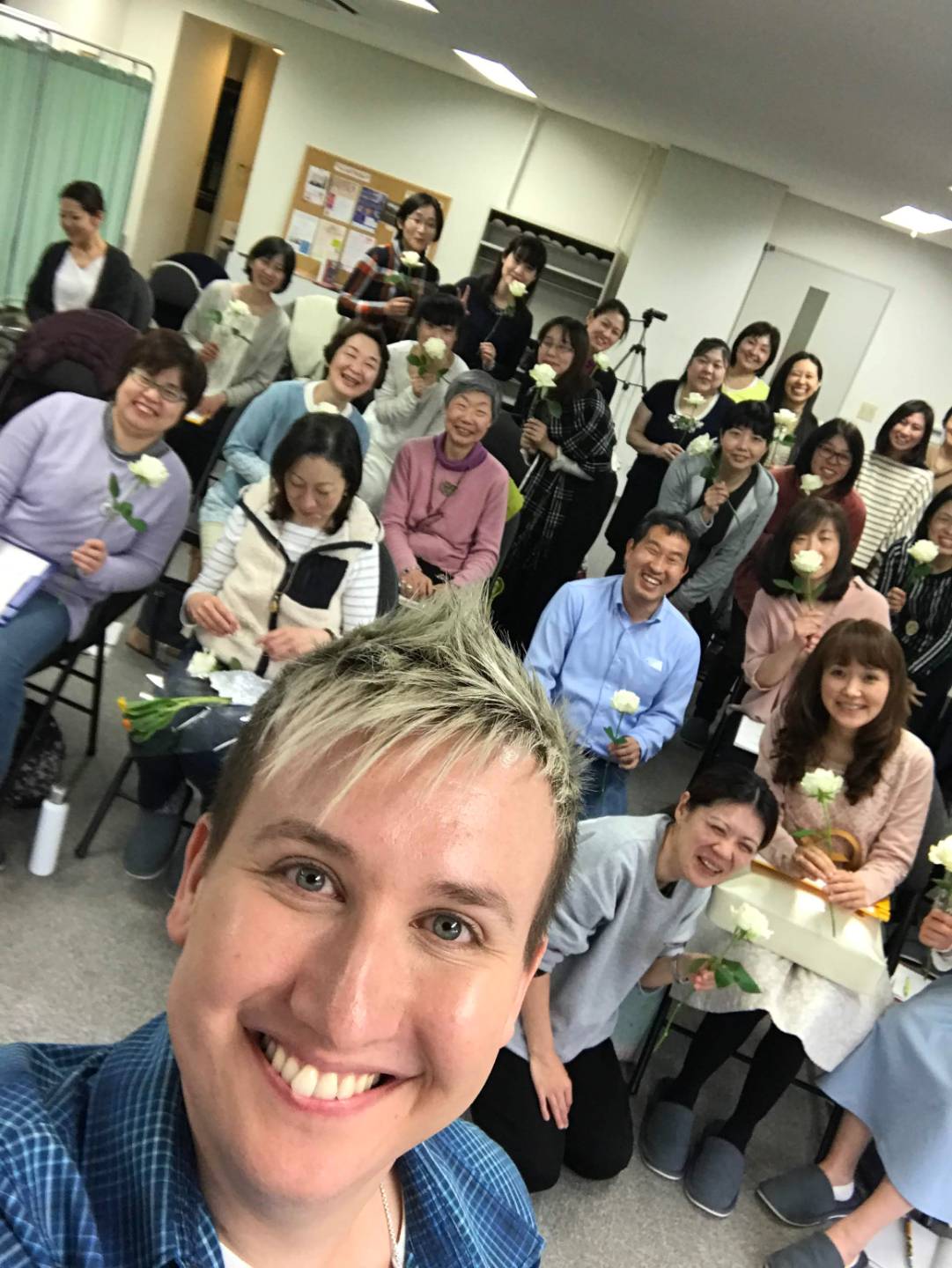 Robert Reeves with a Flower Therapy audience in Japan holding white roses