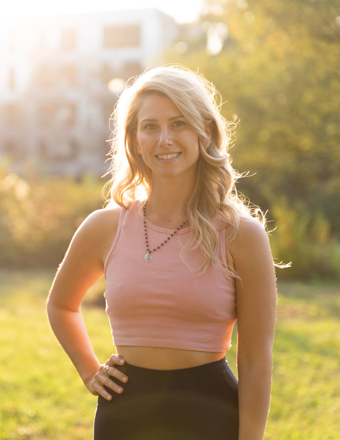Photo of Rebecca Michelle, meditation coach who offers personlized meditation classes online. She is standing outside smiling with one hand on her hip.