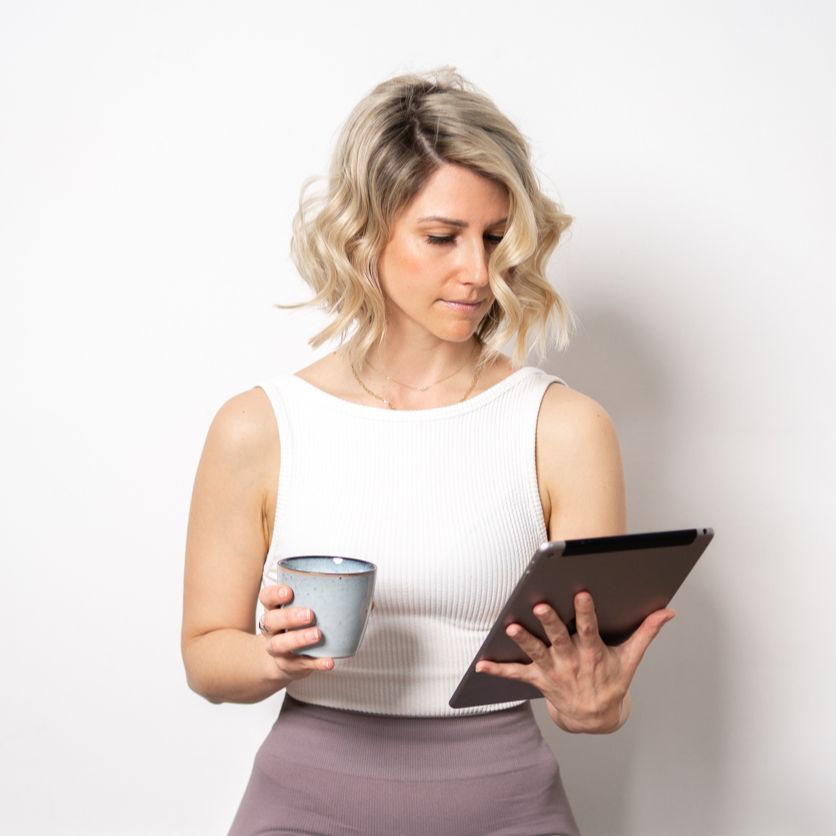 Photo of Rebecca Michelle, a private meditation coach sitting with a cup in her hand and an i-pad in her other hand.