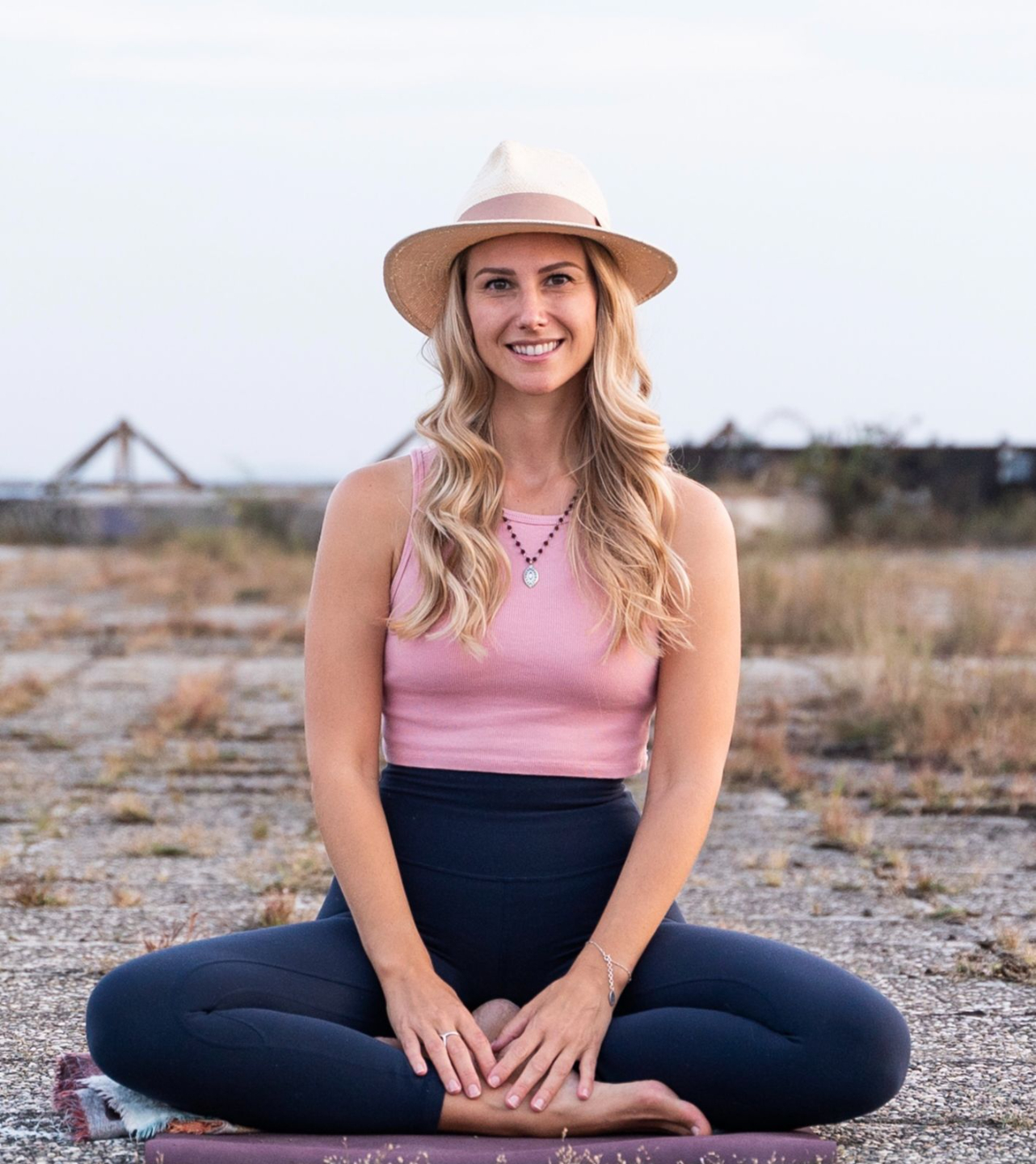 Photo of Rebecca Michelle, a personal meditation coach sitting on the ground cross legged outside.