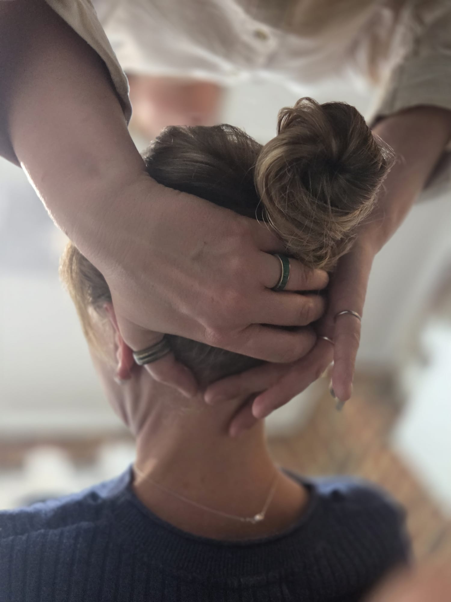 Hands supporting the head and neck during seated soft tissue practice.