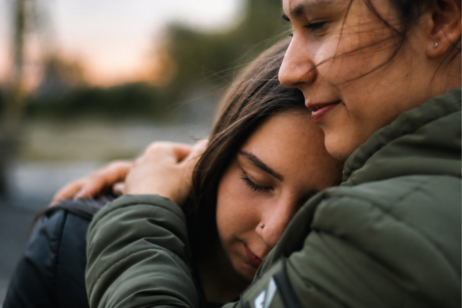 A teen resting their head on a parent's shoulder in a comforting embrace
