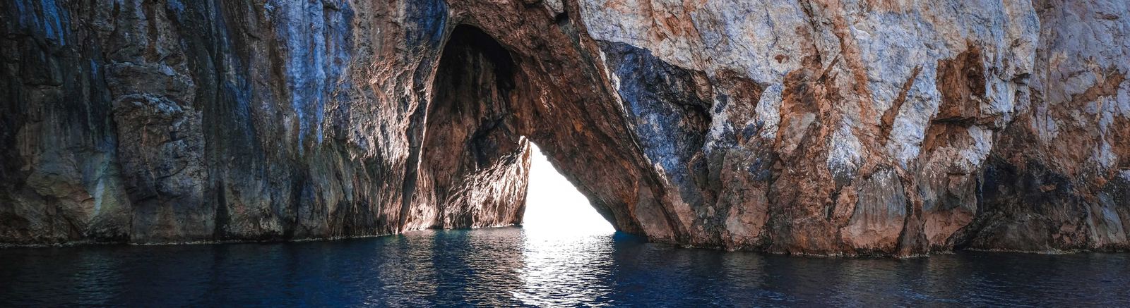 Light through a stone arch at the mouth of a sea cave