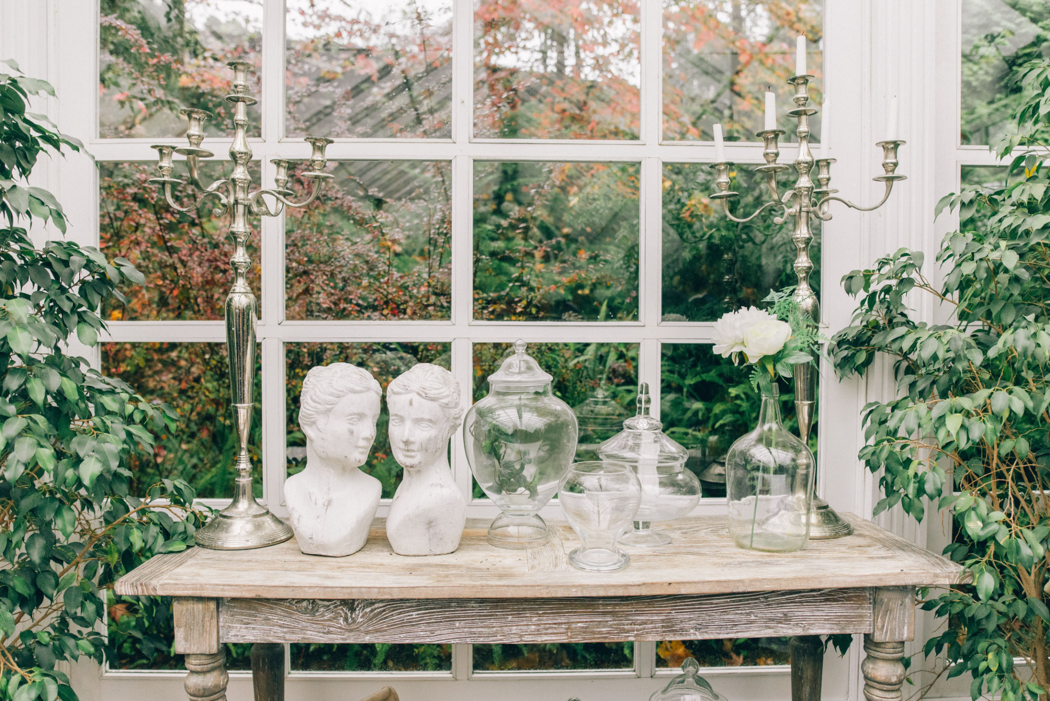 A conservatory still life with classical busts and candlelight