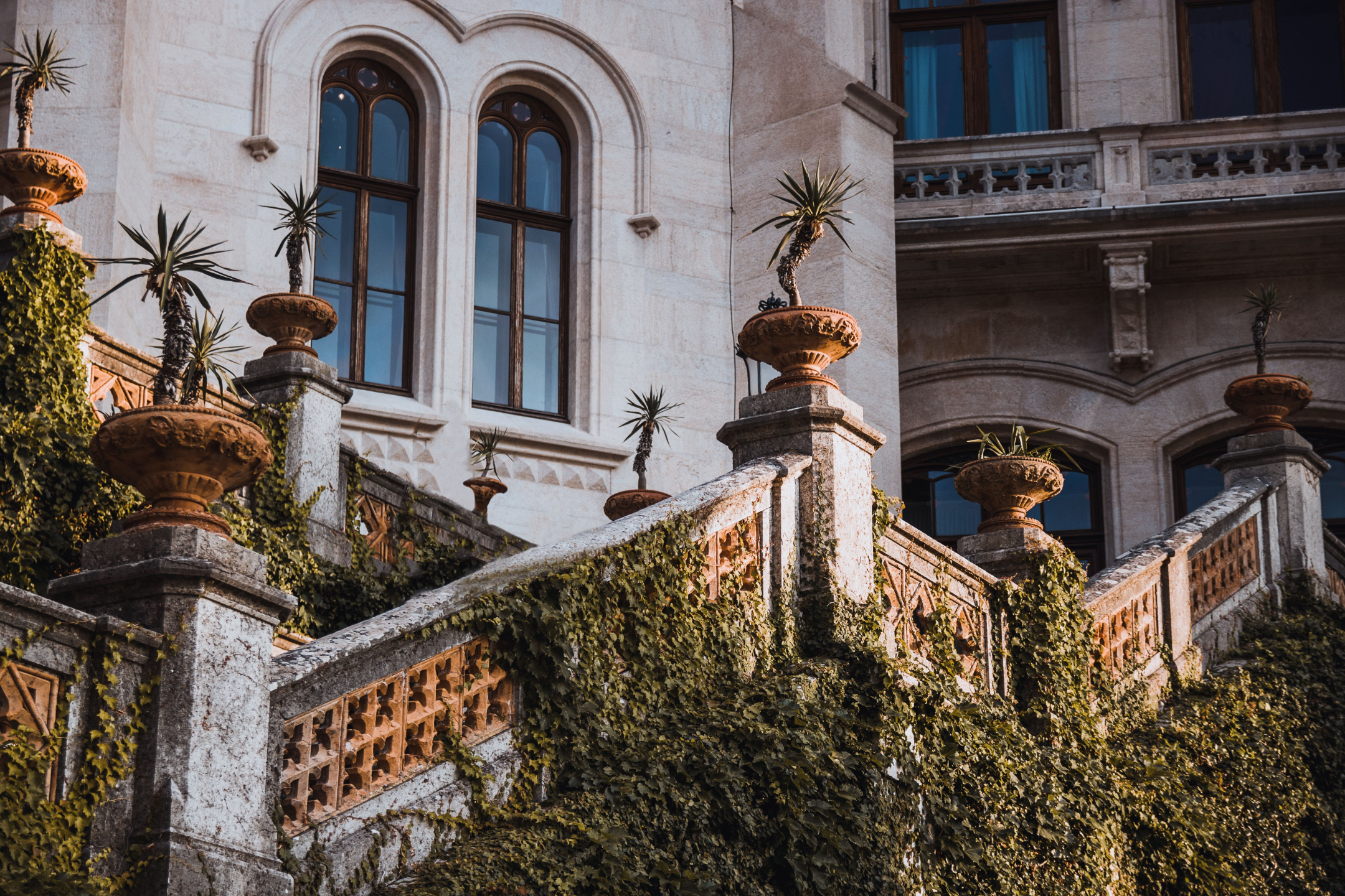 An ivy-covered villa staircase with classical urns