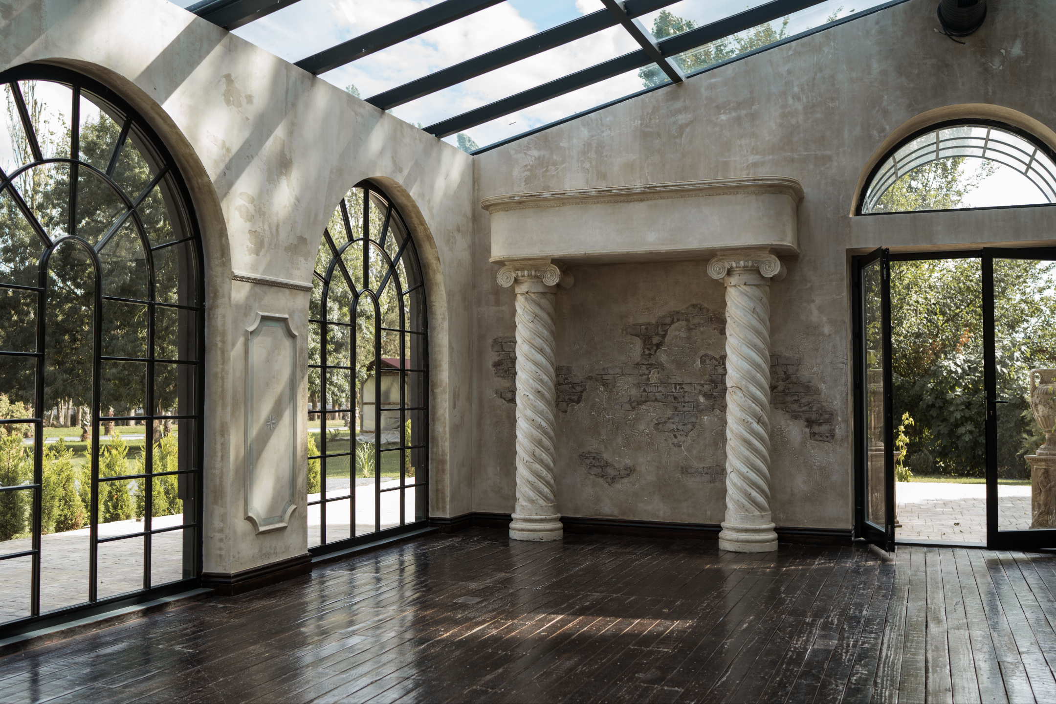 A light-filled conservatory with arched windows and an open door onto a garden