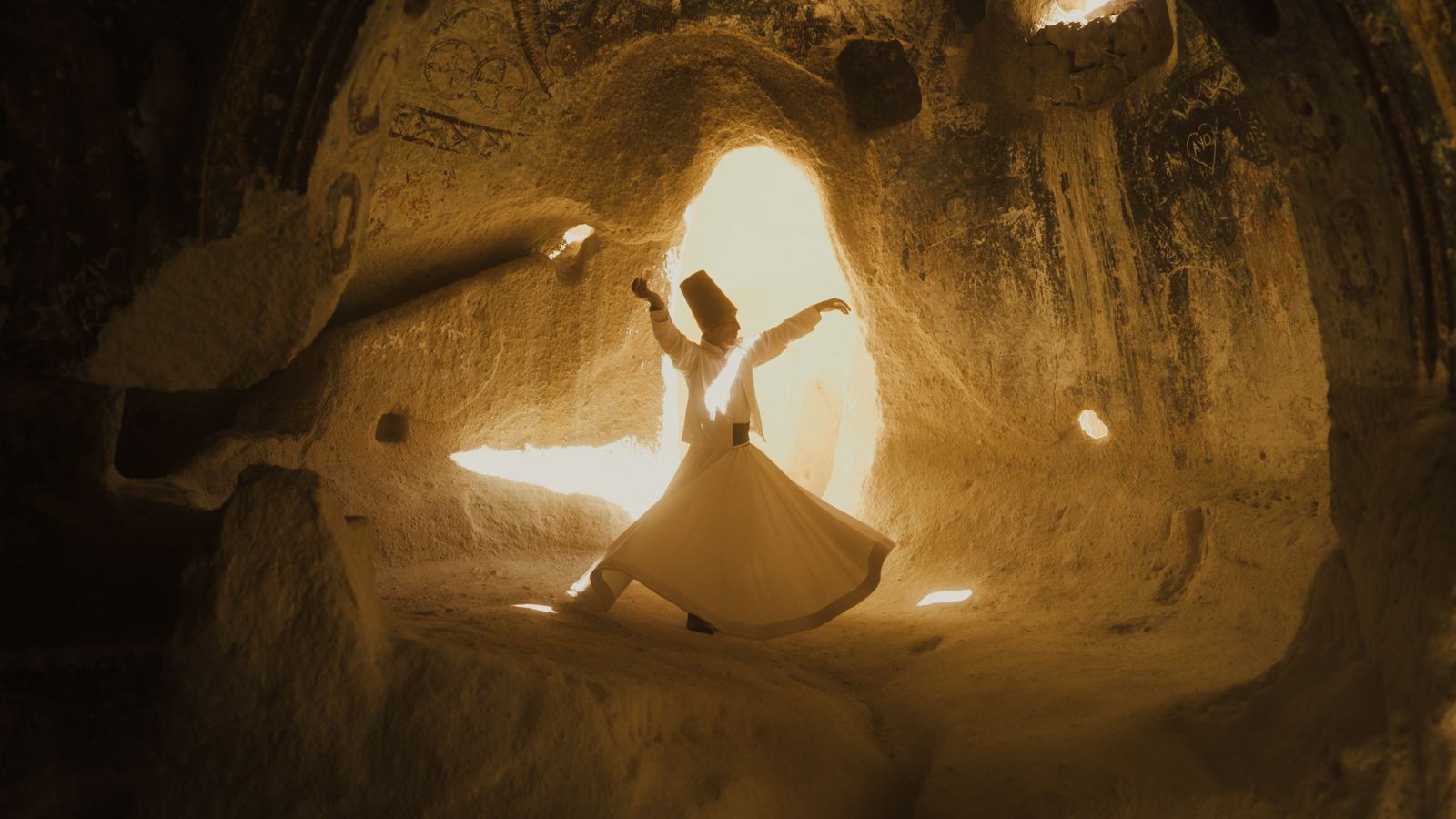 A dervish turning in a candlelit stone chamber