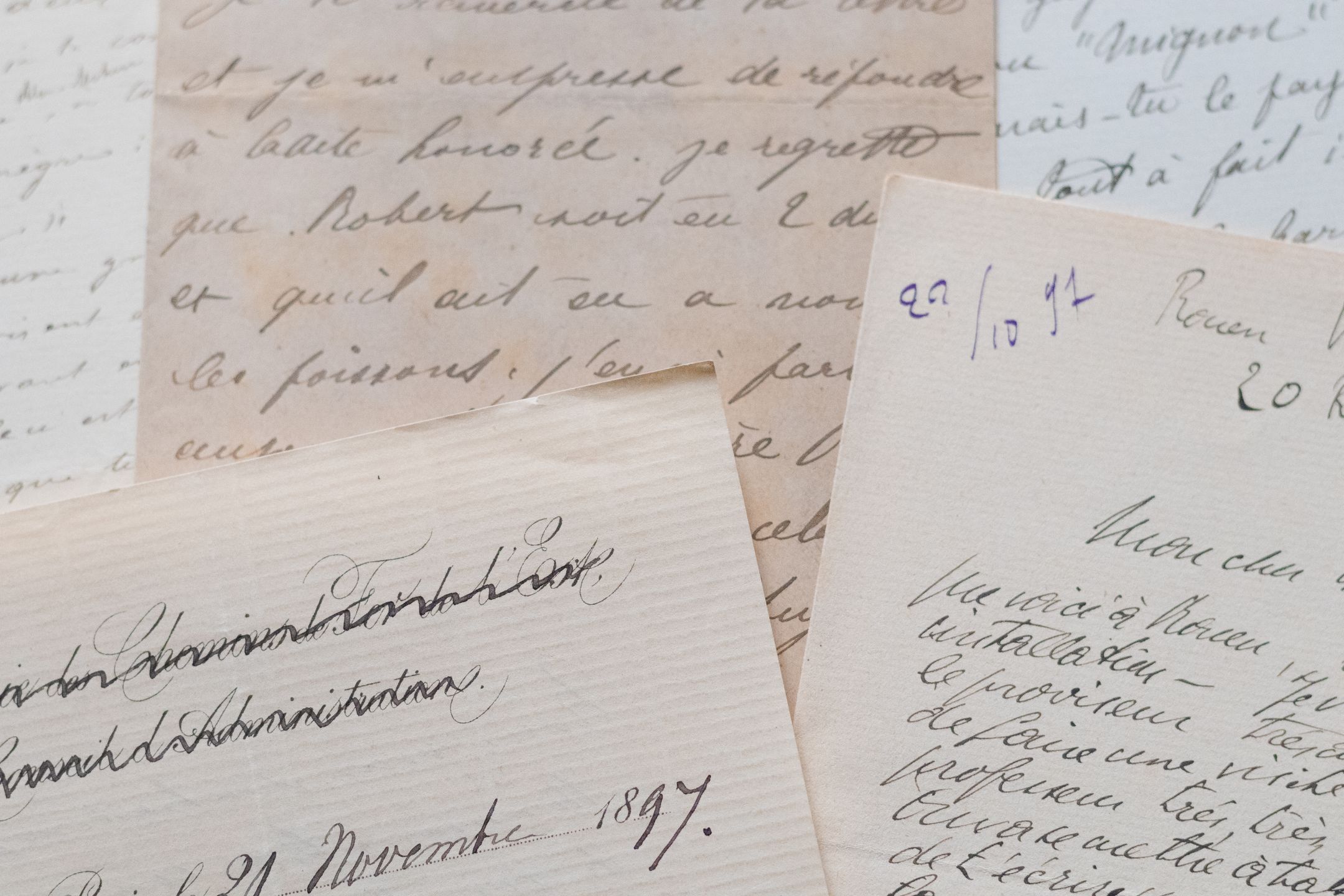 Handwritten letters in ink on aged paper, overlapping on a table.