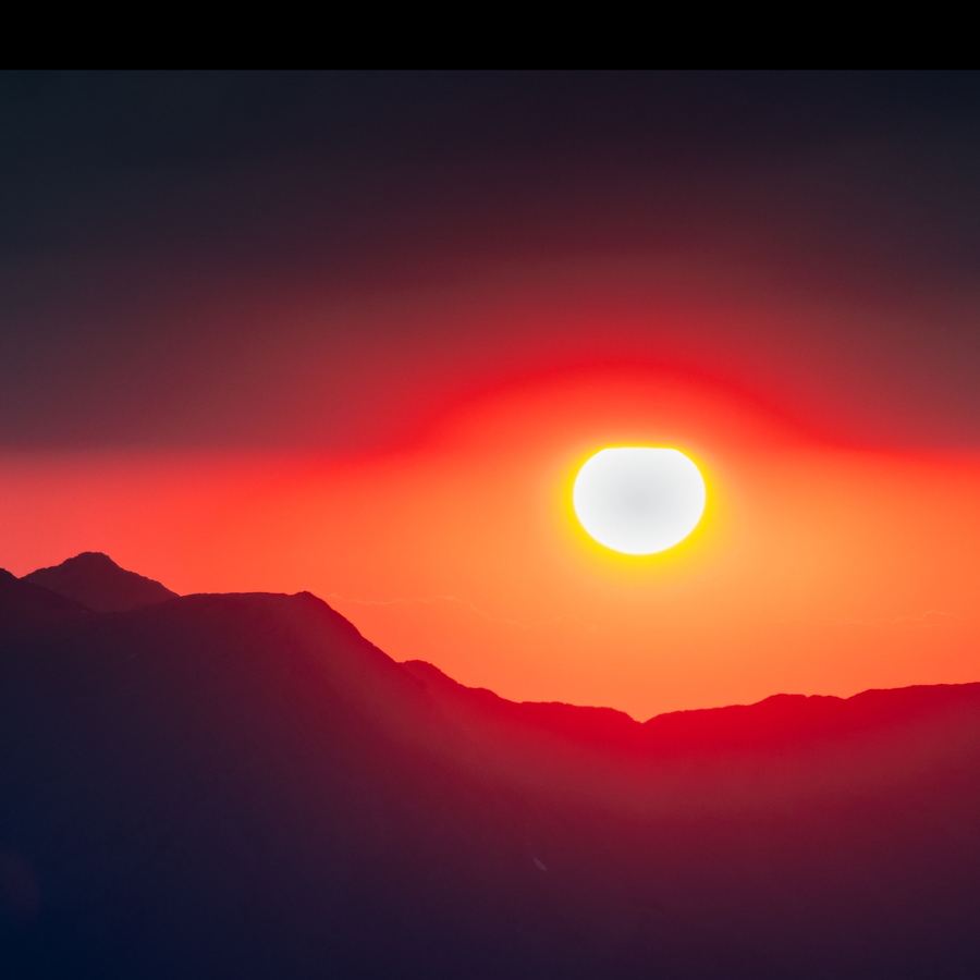 The sun setting behind a mountain ridge