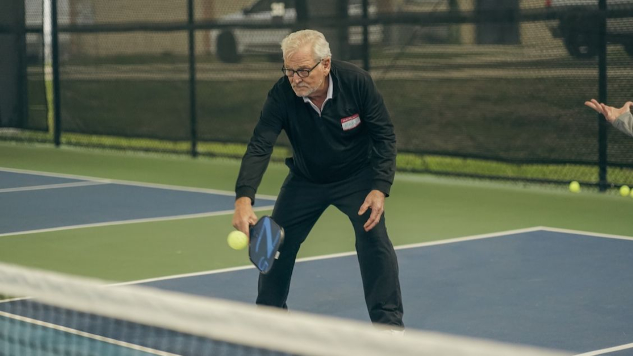 Pickleball player bending low at the NVZ line to hit a controlled dink