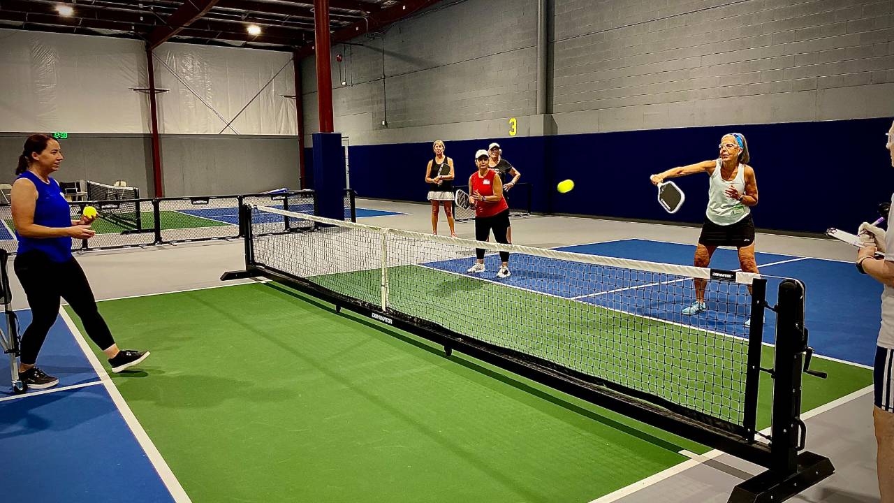 Player hitting a volley at the non-volley zone line during an indoor pickleball camp