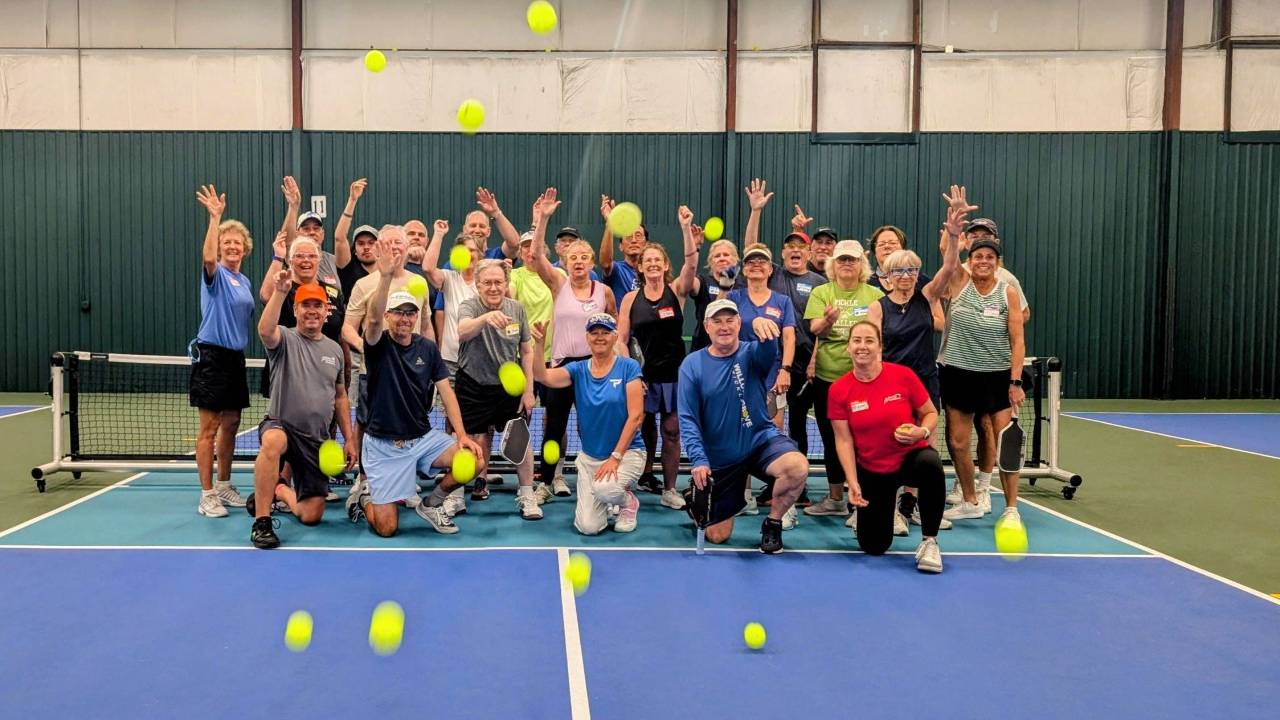 Group of pickleball players posing together on an indoor court after a camp session