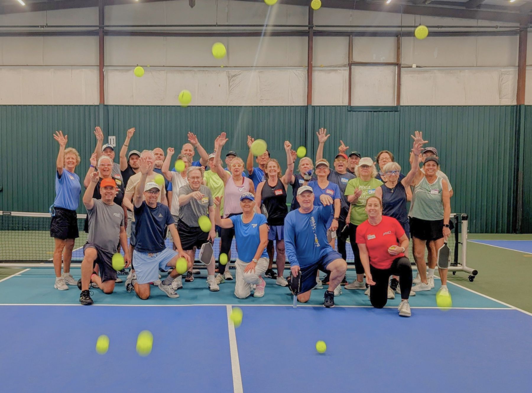 Happy pickleball players at camp tossing pickleballs toward the camera.