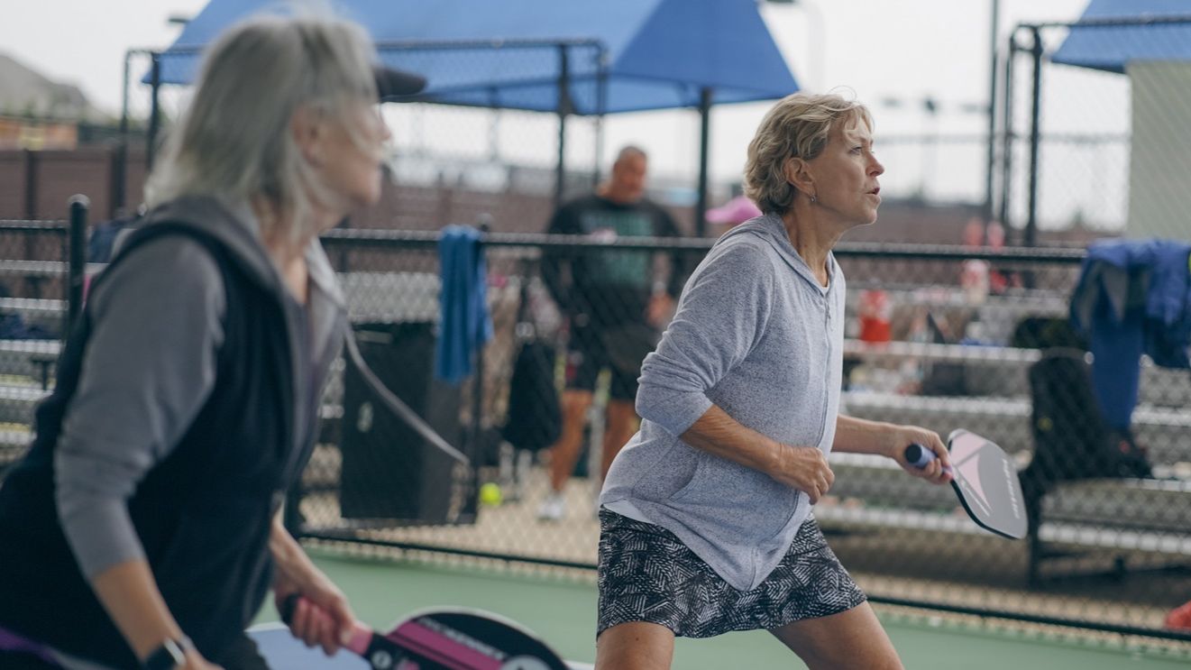 Two women pickleball players positioned at the NVZ line during a doubles rally