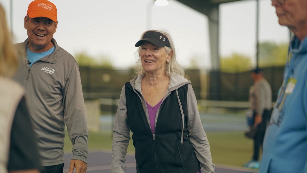 Pickleball players smiling and talking together on the court between games