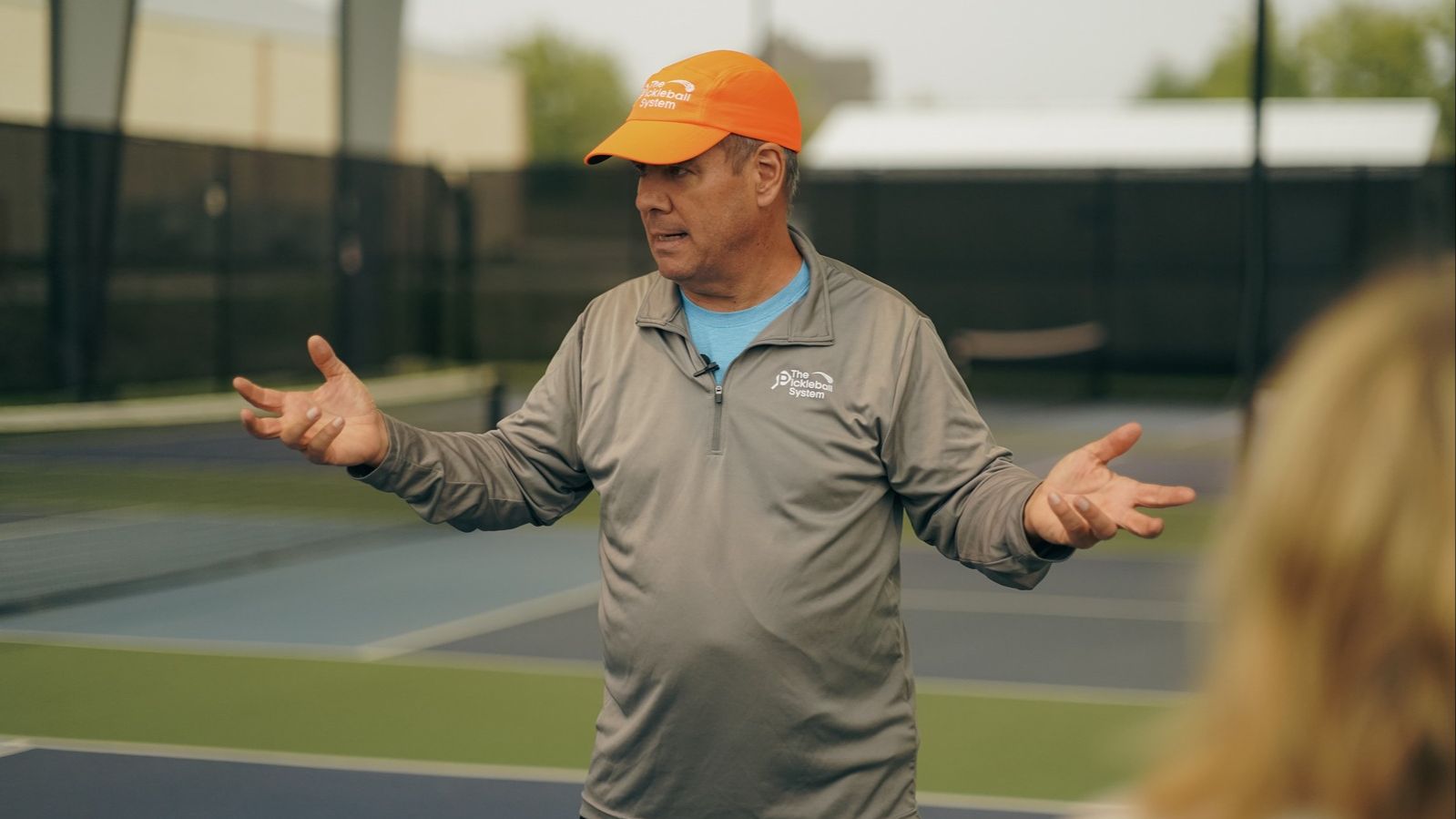 Tony Roig on a pickleball court gesturing with open hands