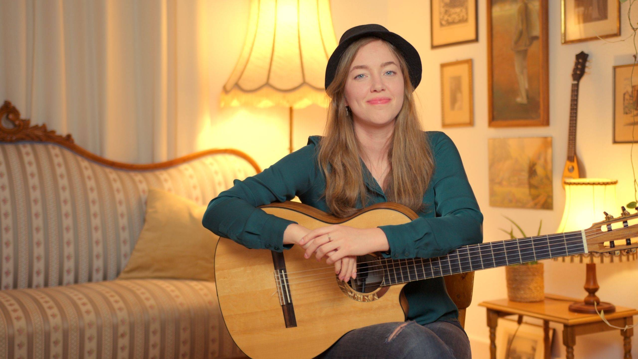 Karlijn Langendijk with her guitar in a warmly lit living room