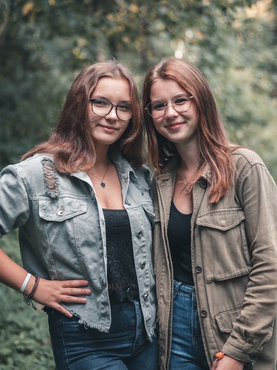 Two friends smiling side by side outdoors
