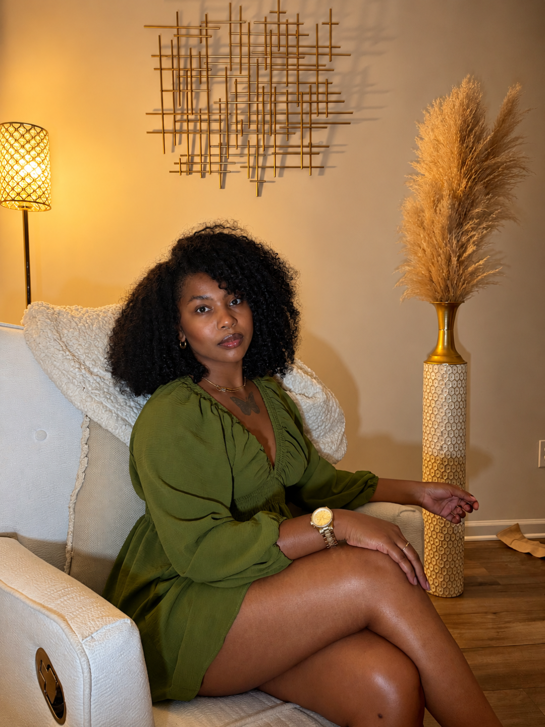 Indigo Ayira seated in a warm living room, wearing an olive dress