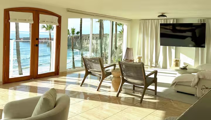 A sunlit lounge with arched doors opening onto palms and the ocean